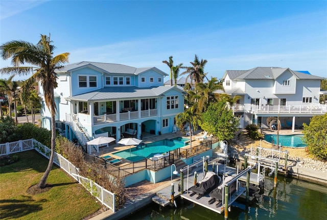 rear view of property featuring a lawn, a patio, a fenced backyard, a balcony, and boat lift