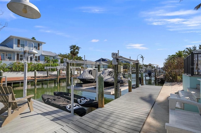 dock area with boat lift, a residential view, and a water view