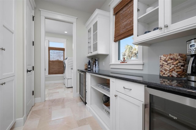 718 Key Royale Dr, Holmes Beach, FL 34217 - kitchen with beverage cooler, white cabinetry, dark stone counters, washer / clothes dryer, and glass insert cabinets