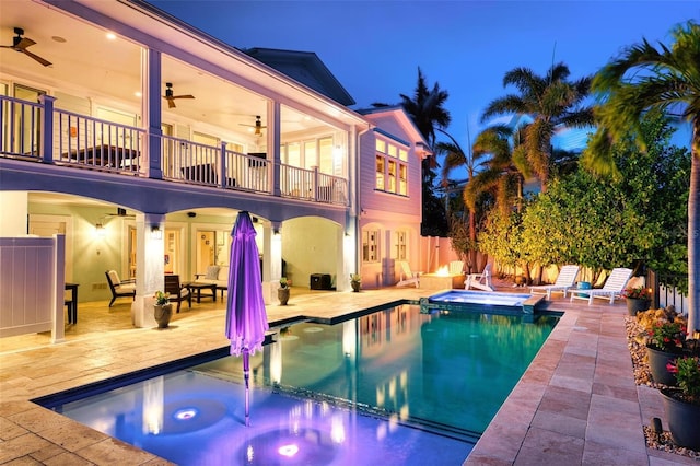 718 Key Royale Dr, Holmes Beach, FL 34217 - pool at night featuring ceiling fan, a patio, a pool with connected hot tub, and fence