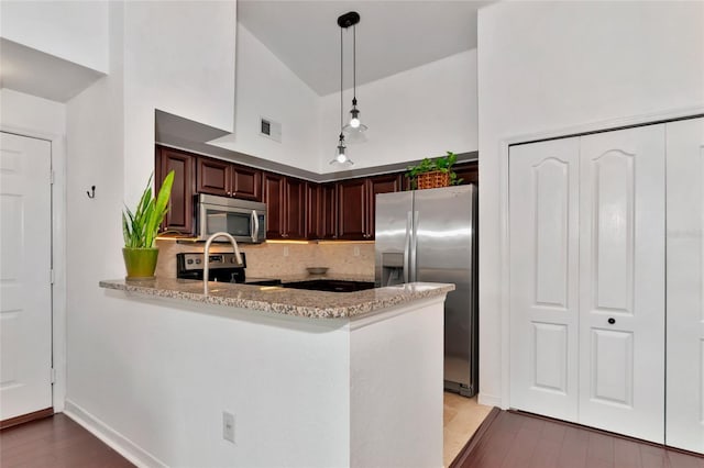 kitchen with pendant lighting, stainless steel appliances, light stone counters, decorative backsplash, and kitchen peninsula