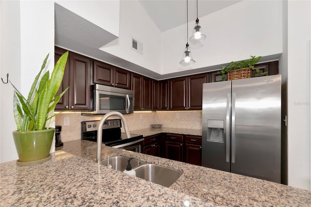 kitchen with pendant lighting, dark brown cabinetry, stainless steel appliances, and backsplash