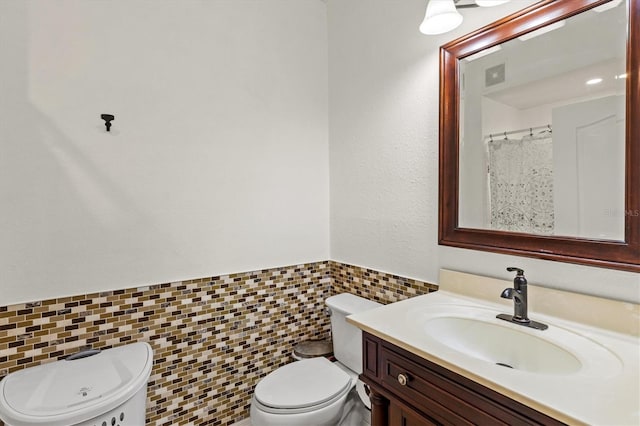 bathroom with vanity, tile walls, and toilet