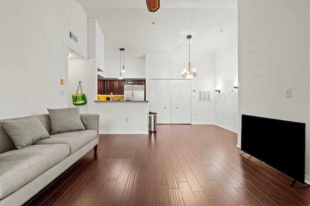 living room with a towering ceiling, a chandelier, and dark hardwood / wood-style flooring