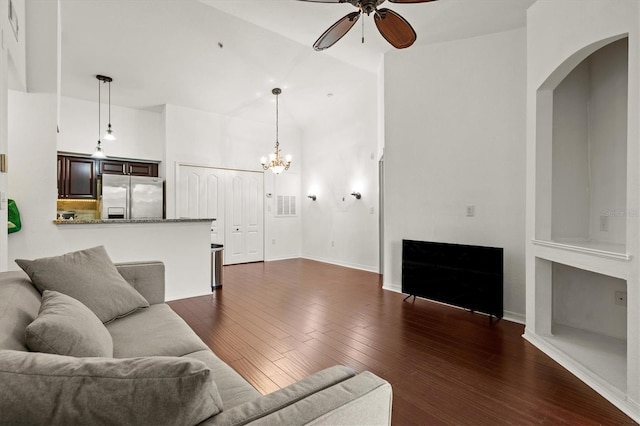 living room with dark hardwood / wood-style flooring and ceiling fan with notable chandelier