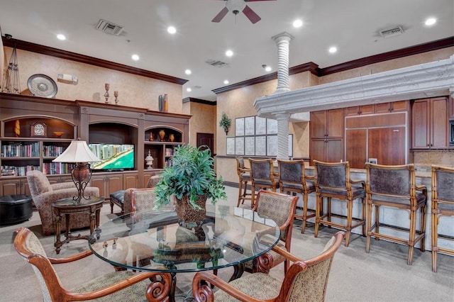 dining room featuring ceiling fan, light colored carpet, ornamental molding, and built in shelves