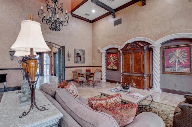 living room featuring crown molding, a towering ceiling, decorative columns, a notable chandelier, and beamed ceiling