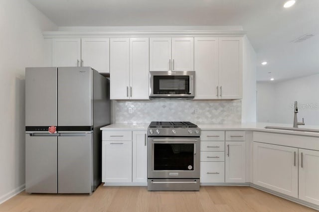 kitchen featuring white cabinetry, stainless steel appliances, tasteful backsplash, sink, and light wood-type flooring