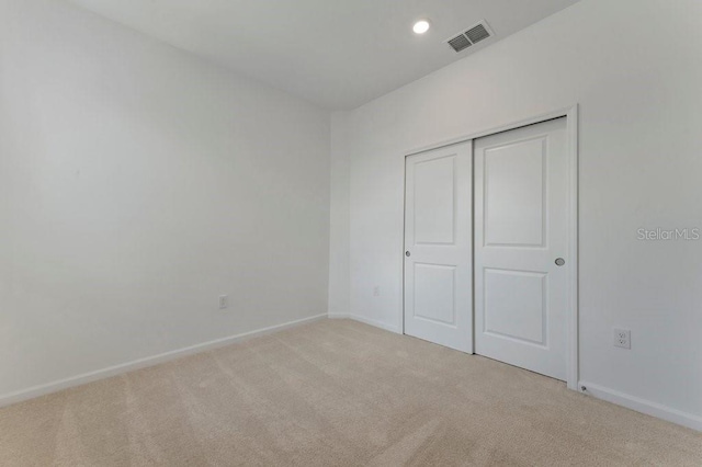 unfurnished bedroom featuring light carpet and a closet