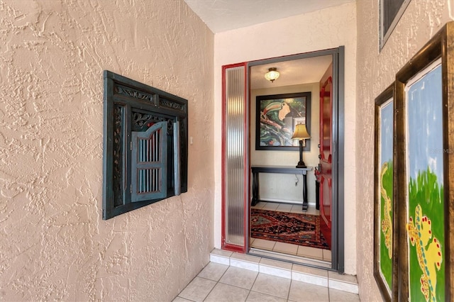 hallway with tile patterned floors and a textured wall