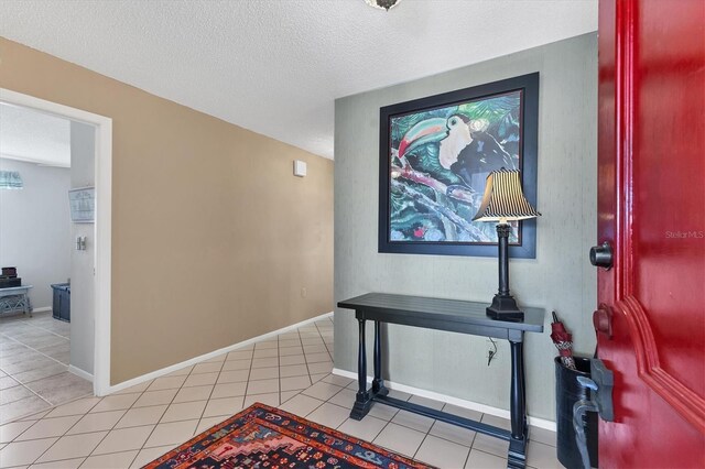 interior space with light tile patterned floors, baseboards, and a textured ceiling