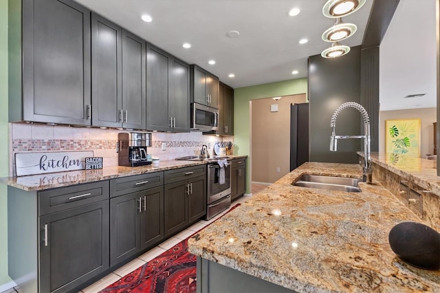 kitchen with a sink, stainless steel appliances, light stone countertops, and tasteful backsplash