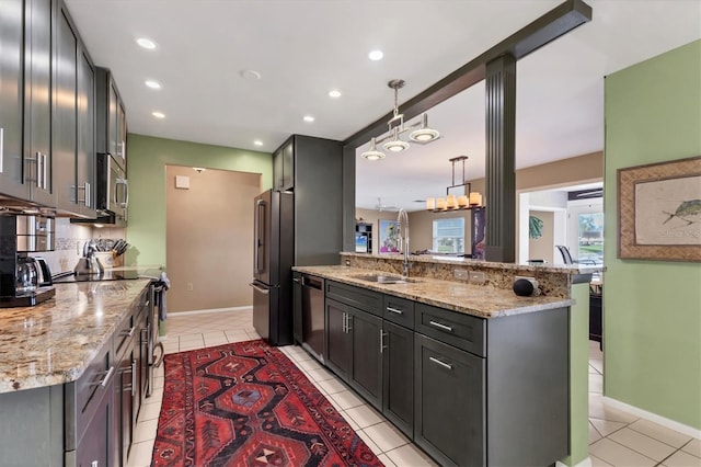 kitchen featuring dishwashing machine, a peninsula, freestanding refrigerator, a sink, and tasteful backsplash