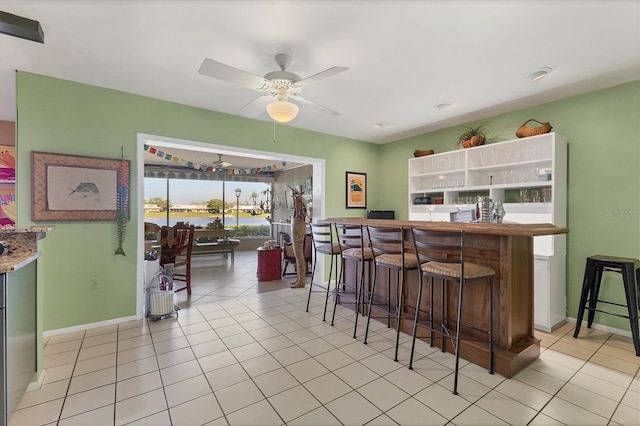 kitchen with light tile patterned floors, baseboards, and a ceiling fan