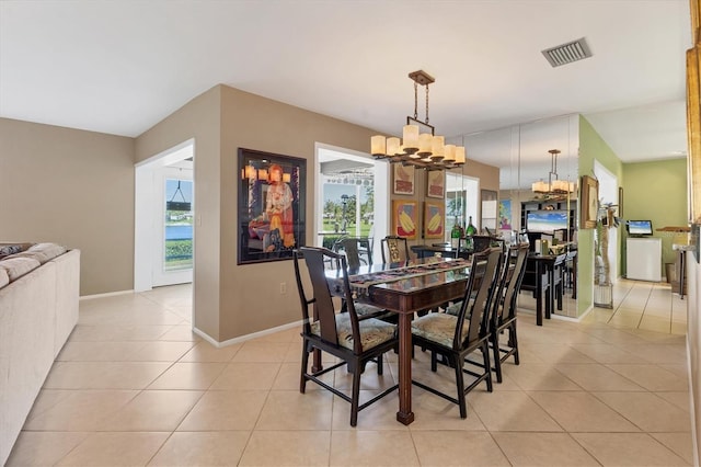 dining space featuring light tile patterned flooring, baseboards, visible vents, and a chandelier