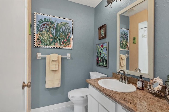 bathroom featuring toilet, tile patterned flooring, baseboards, vanity, and a textured wall