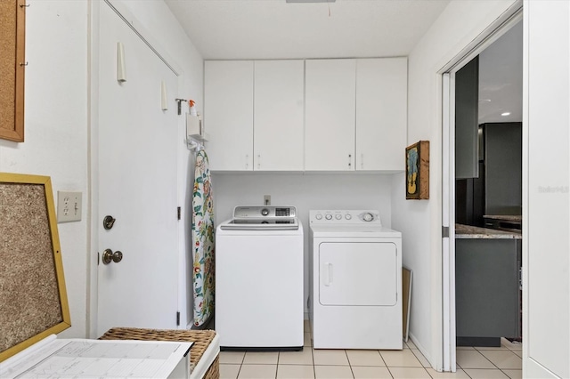 washroom featuring light tile patterned floors, cabinet space, and washing machine and dryer