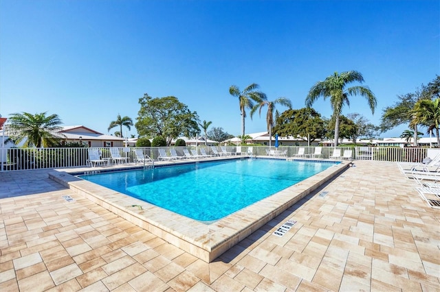 community pool with a patio area and fence