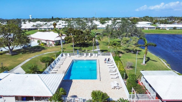 community pool featuring fence, a water view, and a residential view