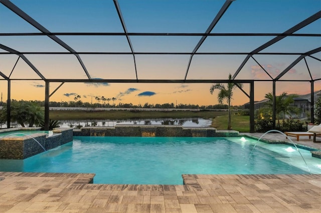 pool at dusk with pool water feature, a lanai, and a water view