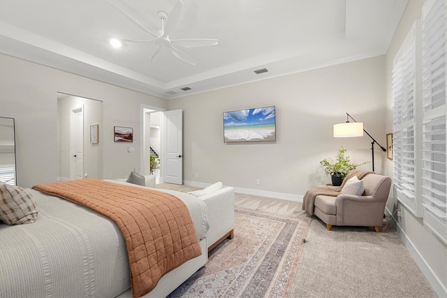 carpeted bedroom featuring ceiling fan and a raised ceiling