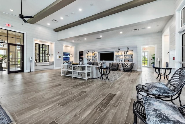 living room featuring wooden walls, ceiling fan, and french doors