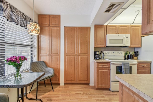 kitchen featuring white appliances, a textured ceiling, and light wood-type flooring