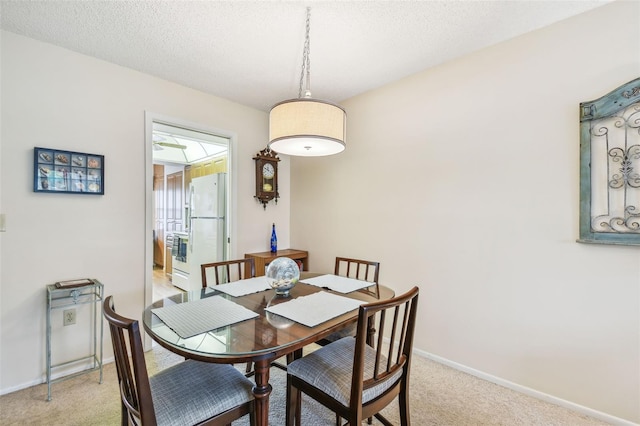 dining space with light colored carpet and a textured ceiling