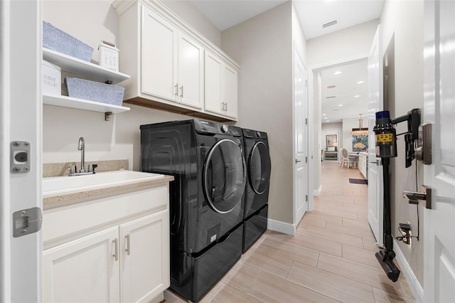 washroom with cabinets, sink, and independent washer and dryer