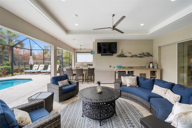 living room with a raised ceiling and ceiling fan