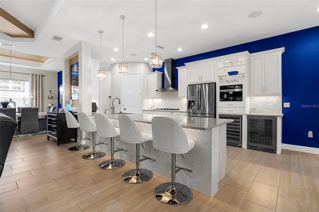 kitchen with white cabinetry, wall chimney range hood, beverage cooler, and stainless steel fridge with ice dispenser