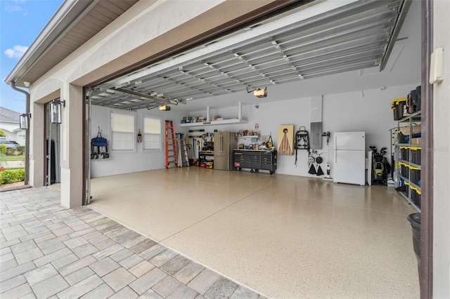 garage with a garage door opener, white fridge, and stainless steel refrigerator