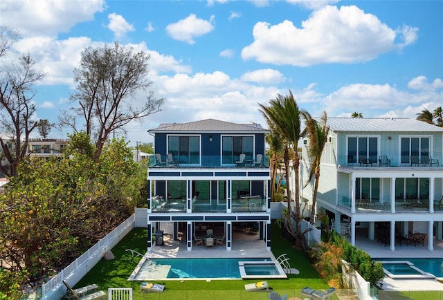 back of property featuring a yard, a patio, a balcony, and a pool with connected hot tub