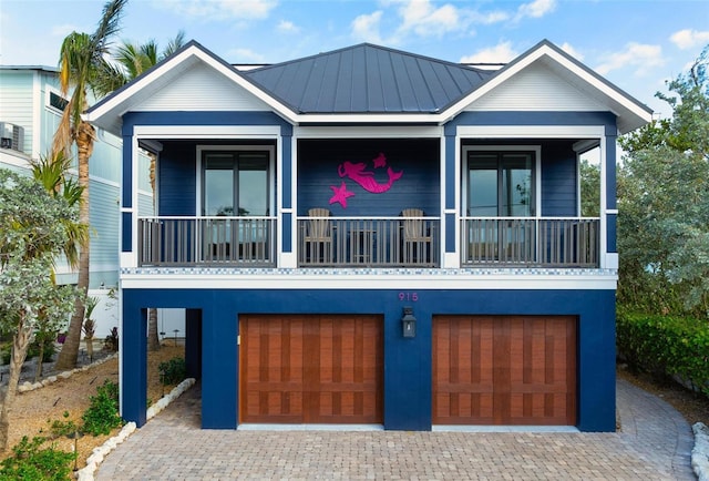 915 N Shore Dr, Anna Maria, FL 34216 - view of front of home with a standing seam roof, metal roof, driveway, a garage, and a balcony