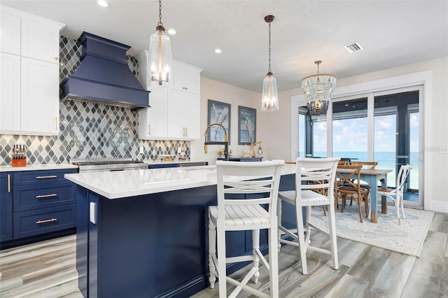 915 N Shore Dr, Anna Maria, FL 34216 - kitchen featuring light countertops, blue cabinetry, a chandelier, premium range hood, and a center island