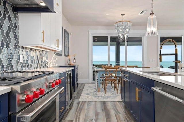 915 N Shore Dr, Anna Maria, FL 34216 - kitchen featuring blue cabinetry, appliances with stainless steel finishes, wood finished floors, a sink, and a notable chandelier