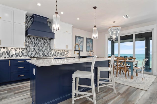 915 N Shore Dr, Anna Maria, FL 34216 - kitchen with custom range hood, light countertops, a notable chandelier, and blue cabinetry