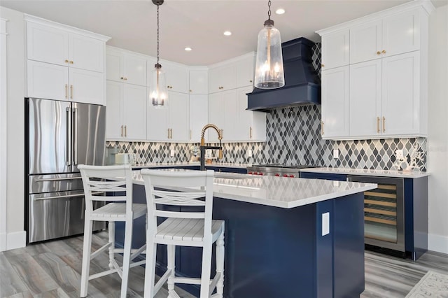 915 N Shore Dr, Anna Maria, FL 34216 - kitchen with high end refrigerator, wall chimney range hood, light wood-style flooring, and wine cooler