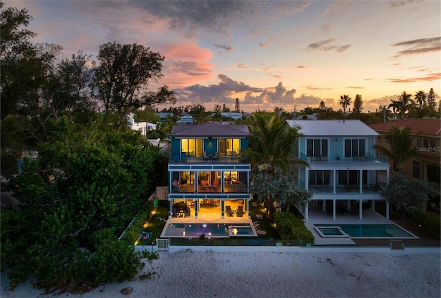 915 N Shore Dr, Anna Maria, FL 34216 - back of property at dusk featuring fence private yard, metal roof, a balcony, and a patio area