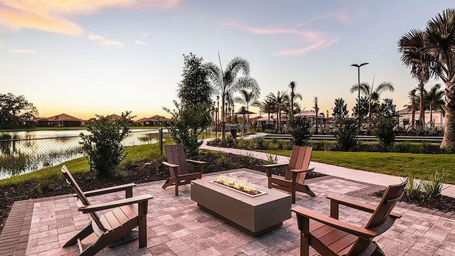 patio terrace at dusk with a water view and a fire pit