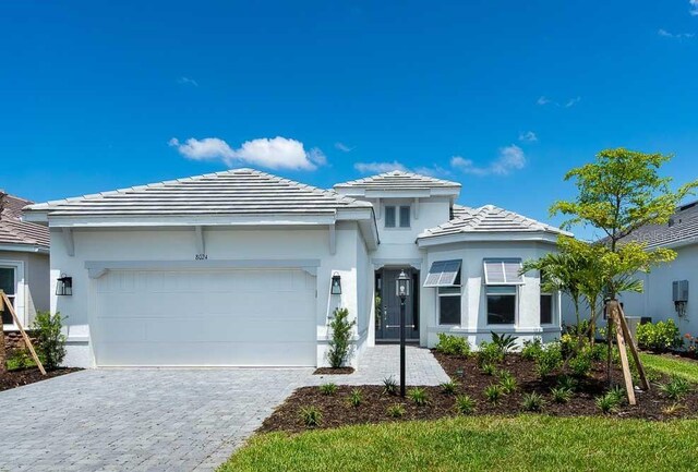 8024 Moonbeam Ave, Sarasota, FL 34241 - prairie-style house with a garage, decorative driveway, stucco siding, and a tile roof