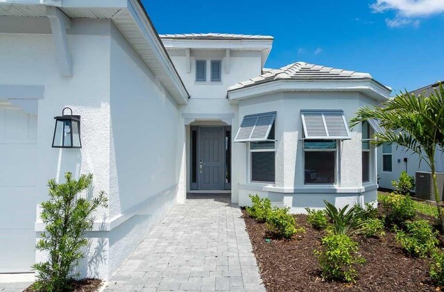 8024 Moonbeam Ave, Sarasota, FL 34241 - property entrance featuring cooling unit, a tile roof, and stucco siding