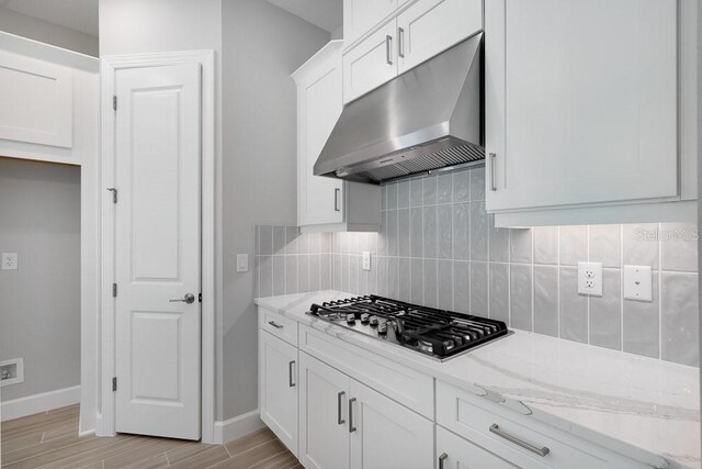 8024 Moonbeam Ave, Sarasota, FL 34241 - kitchen featuring under cabinet range hood, stainless steel gas stovetop, white cabinets, light stone counters, and baseboards