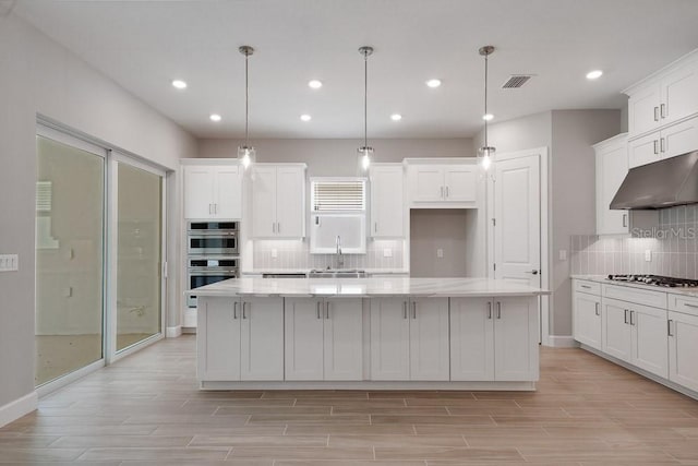 8024 Moonbeam Ave, Sarasota, FL 34241 - kitchen featuring under cabinet range hood, a sink, stainless steel appliances, decorative backsplash, and white cabinetry