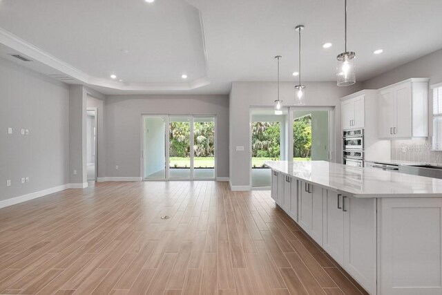 8024 Moonbeam Ave, Sarasota, FL 34241 - kitchen with baseboards, white cabinets, a spacious island, light wood finished floors, and recessed lighting