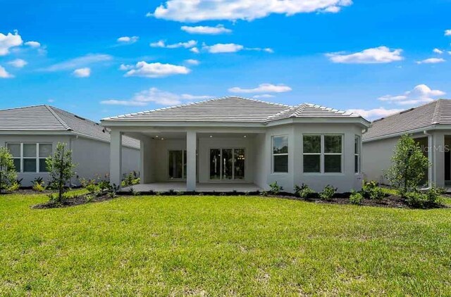8024 Moonbeam Ave, Sarasota, FL 34241 - rear view of house featuring a yard, a patio area, stucco siding, and a tiled roof