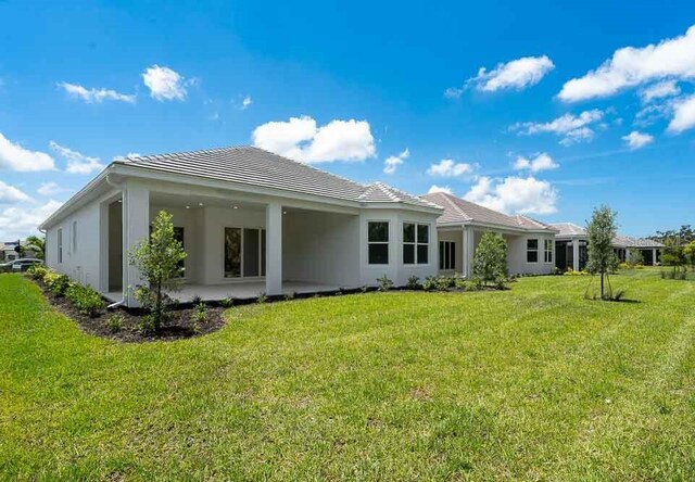 8024 Moonbeam Ave, Sarasota, FL 34241 - rear view of house featuring a patio area, a lawn, and stucco siding