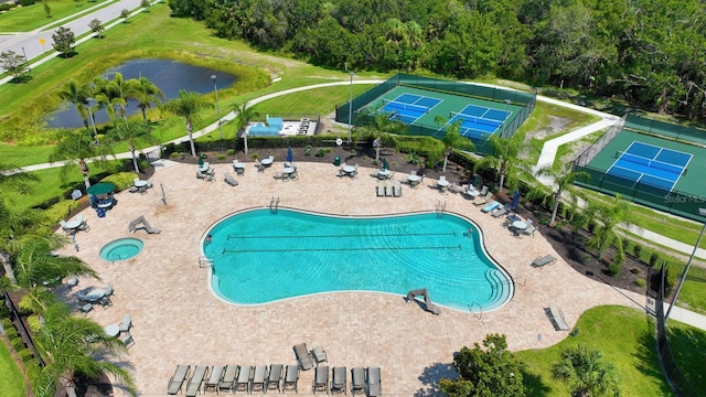 view of swimming pool featuring tennis court and a water view