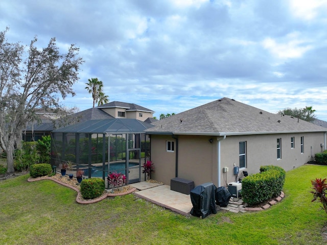 rear view of house with a patio, glass enclosure, and a yard