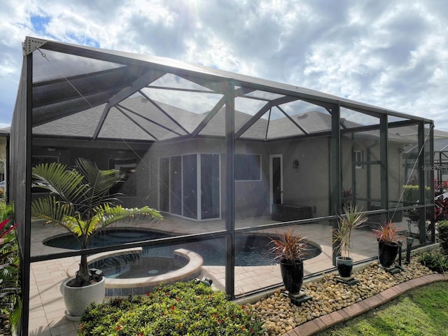 rear view of house with a pool with hot tub, a patio, and glass enclosure